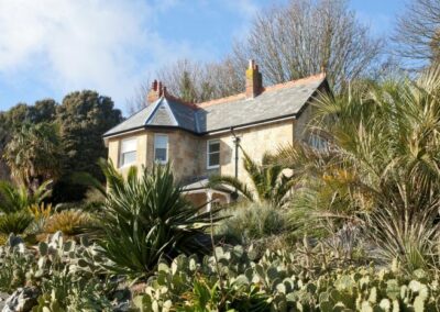 Signal Point Cottage, a yellow brick victorian lodge built within the grounds of Ventnor Botanic Garden. It's surrounded by greenery at it's vantage point within the Arid Garden.