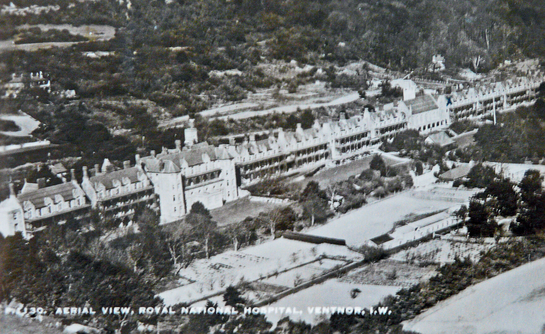 Black and white image showing the total view of the hospital from the air. The 1/4 of a mile long building with windows and wards all facing out to the sea for the best views.